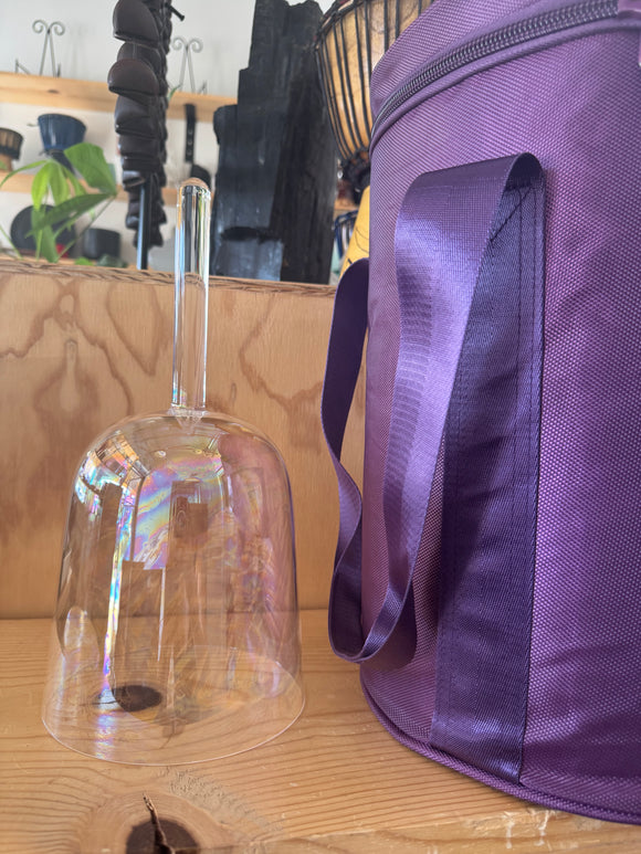 Purple bag and clear bell on a wooden surface with a blurred background